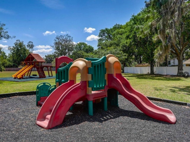 community jungle gym featuring a lawn and fence