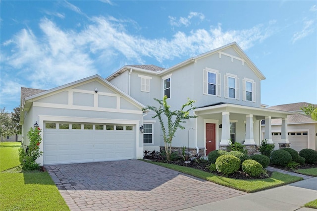 view of front of house featuring decorative driveway, stucco siding, covered porch, a garage, and stone siding