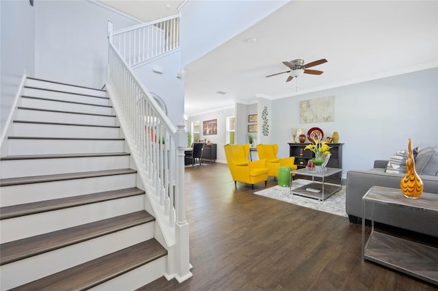 living area featuring ornamental molding, ceiling fan, wood finished floors, baseboards, and stairs