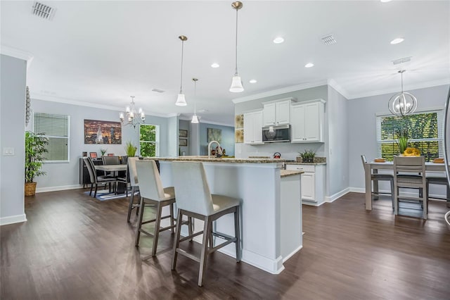 kitchen with a healthy amount of sunlight, stainless steel microwave, visible vents, and an inviting chandelier