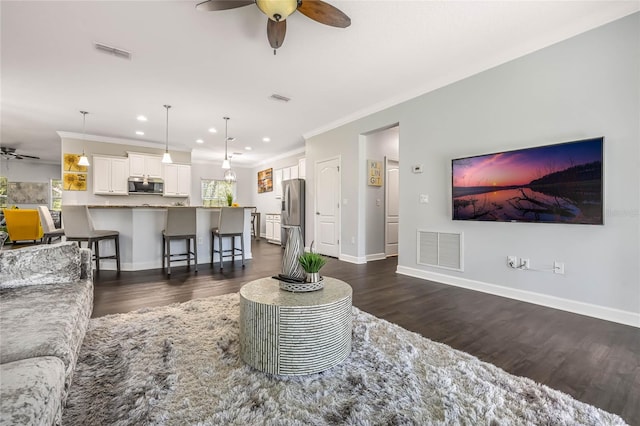 living room featuring crown molding, visible vents, and a ceiling fan