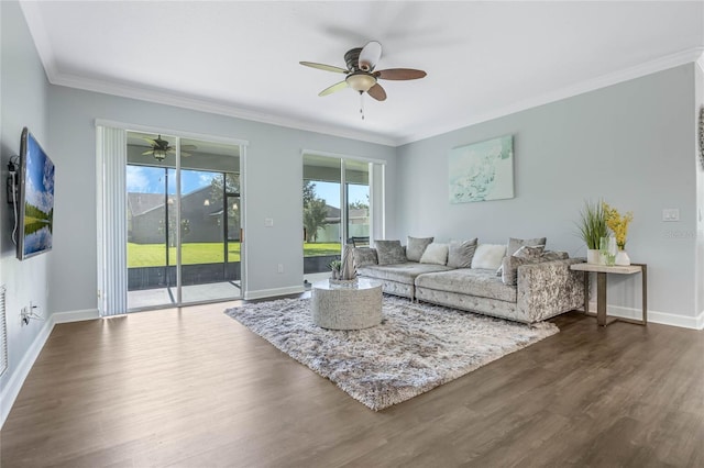 living room featuring dark wood-style floors, crown molding, baseboards, and a ceiling fan