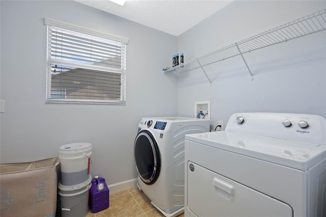 clothes washing area with light tile patterned floors, laundry area, washer and clothes dryer, and baseboards