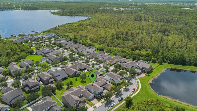 drone / aerial view featuring a water view, a residential view, and a wooded view