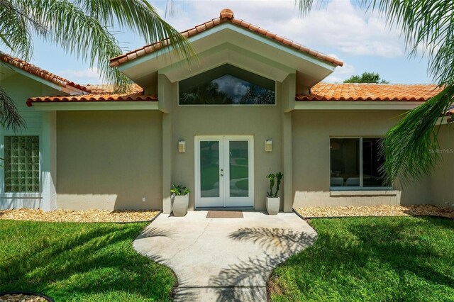 entrance to property with french doors and a lawn