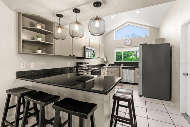 kitchen with stainless steel appliances, a breakfast bar, light tile patterned flooring, kitchen peninsula, and hanging light fixtures