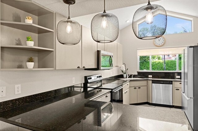 kitchen featuring dark stone countertops, hanging light fixtures, appliances with stainless steel finishes, and a healthy amount of sunlight