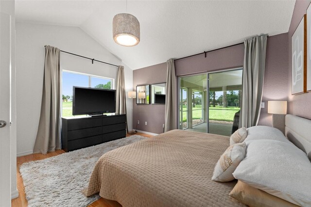 bedroom featuring access to outside, lofted ceiling, and light hardwood / wood-style floors