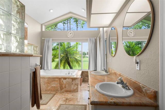 bathroom with tiled tub, vaulted ceiling, and vanity