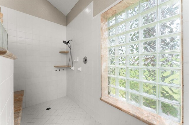 bathroom with lofted ceiling and tiled shower