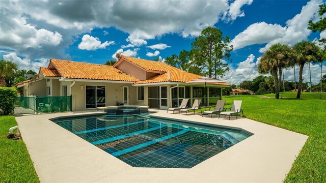 back of house with a pool with hot tub, a patio, a yard, and a sunroom