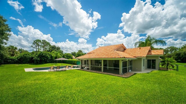 rear view of property with a yard, a sunroom, and a patio area