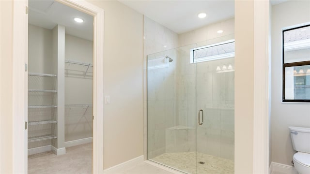 bathroom featuring a shower with shower door and toilet