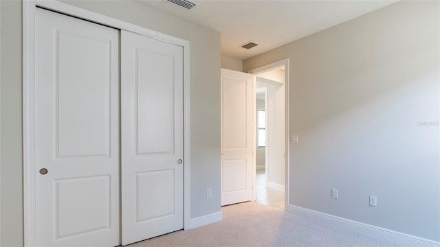 unfurnished bedroom with a closet and light colored carpet