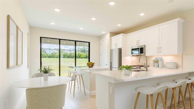 kitchen with sink, white cabinetry, stainless steel appliances, and tasteful backsplash