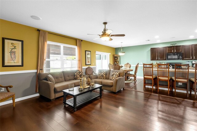 living room featuring ceiling fan and dark hardwood / wood-style flooring