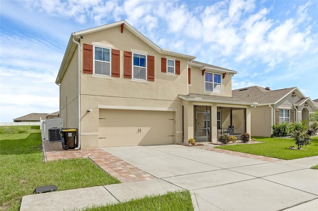 view of front of home with a front yard, driveway, an attached garage, central AC, and stucco siding