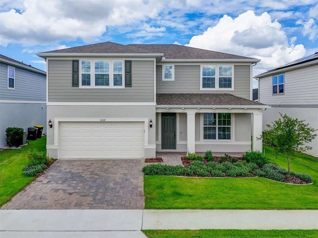 view of front of house with a garage, a shingled roof, decorative driveway, a front lawn, and stucco siding