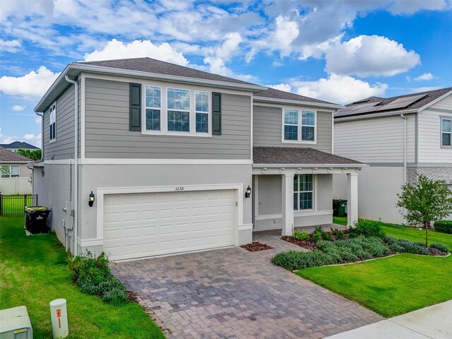 view of front of property featuring a garage, solar panels, and a front lawn