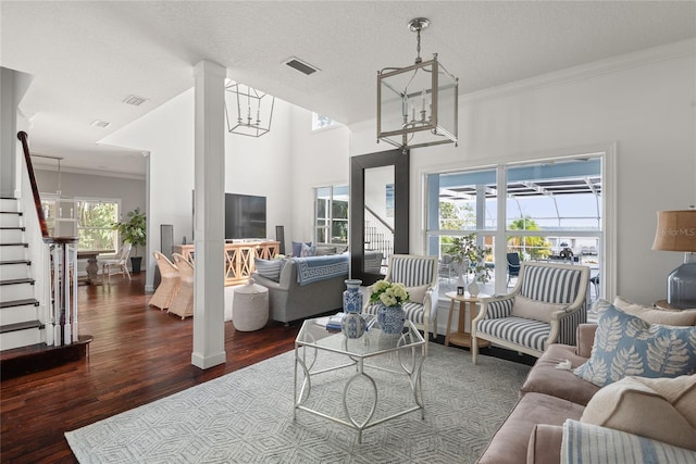 living room featuring dark hardwood / wood-style flooring, crown molding, a textured ceiling, and a notable chandelier