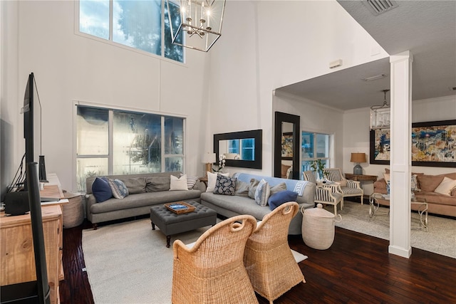 living room with dark wood-type flooring, a chandelier, crown molding, and a high ceiling