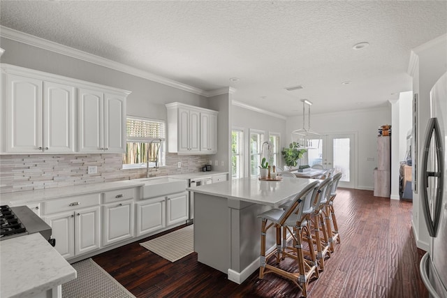 kitchen with pendant lighting, white cabinetry, a center island, and crown molding