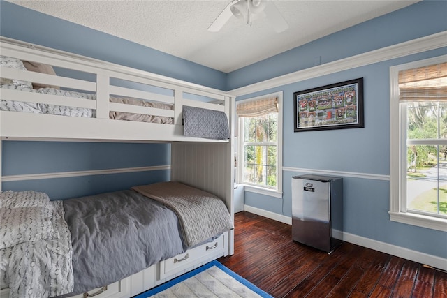 bedroom with ceiling fan, dark hardwood / wood-style floors, stainless steel fridge, and a textured ceiling