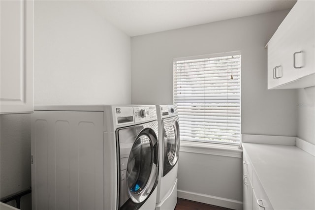 clothes washing area featuring dark wood-type flooring, cabinets, independent washer and dryer, and a healthy amount of sunlight