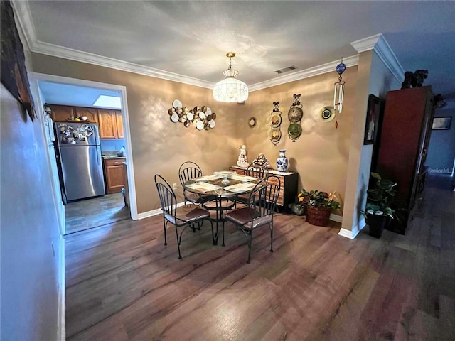 dining space with crown molding, dark wood-type flooring, and a chandelier