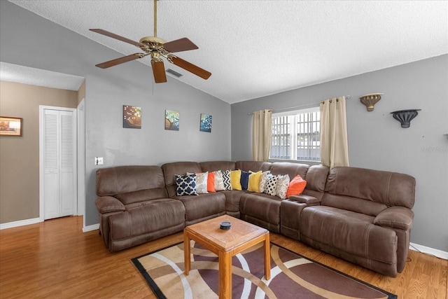 living room featuring light wood-style flooring, vaulted ceiling, and a textured ceiling