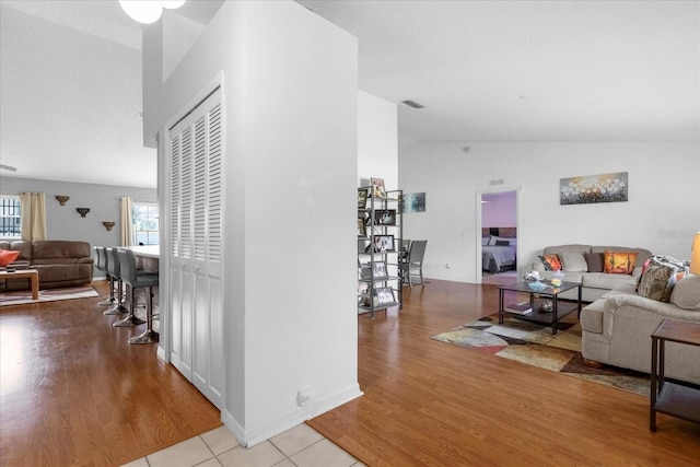 living area with vaulted ceiling, wood finished floors, and visible vents