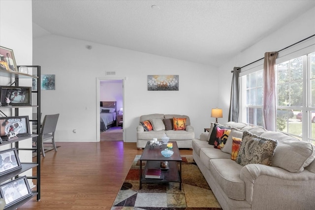 living room with visible vents, vaulted ceiling, a textured ceiling, and wood finished floors