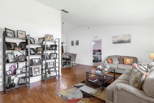 living area with vaulted ceiling, wood finished floors, and visible vents