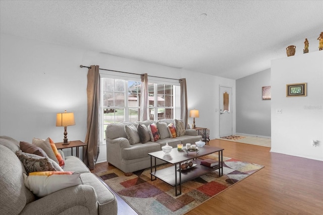 living area with lofted ceiling, a textured ceiling, and wood finished floors