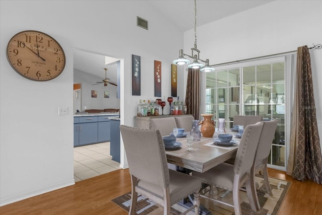 dining space featuring high vaulted ceiling, a ceiling fan, visible vents, and light wood-style floors