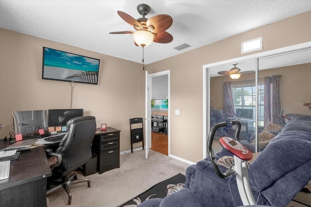 home office featuring ceiling fan, a textured ceiling, light carpet, visible vents, and baseboards