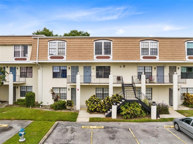 view of property with stairs and uncovered parking