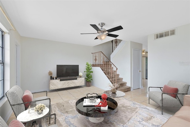 living room featuring light tile patterned floors, ceiling fan, stairs, and visible vents