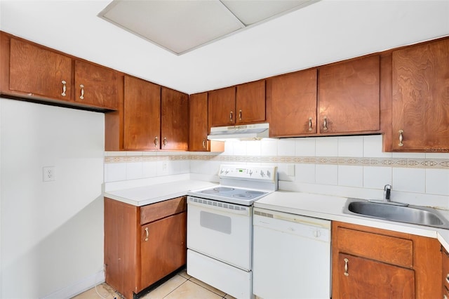 kitchen with under cabinet range hood, white appliances, a sink, light countertops, and tasteful backsplash