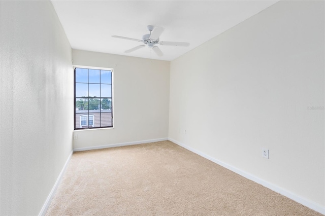 unfurnished room with baseboards, a ceiling fan, and light colored carpet