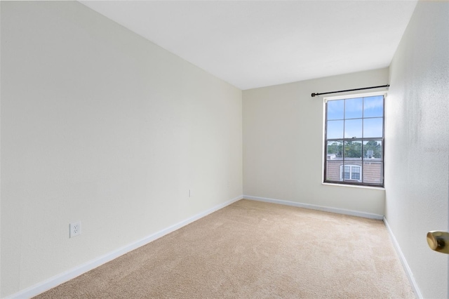 empty room featuring baseboards and light colored carpet