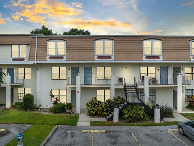 property at dusk featuring uncovered parking and stairway