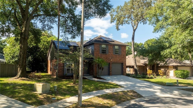 view of front facade with brick siding, solar panels, concrete driveway, a front yard, and fence