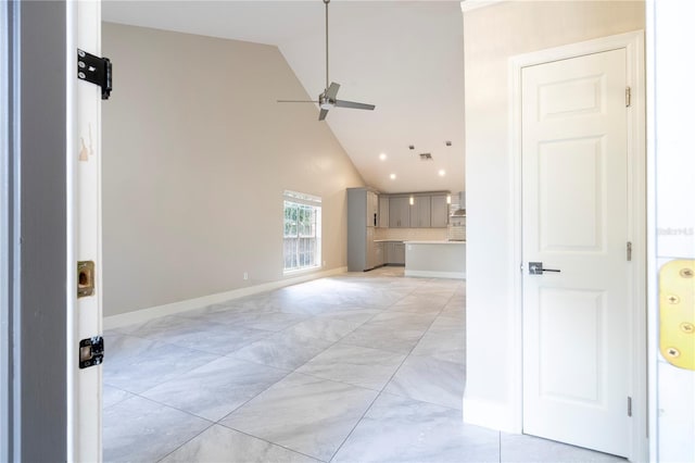 unfurnished living room with a ceiling fan, visible vents, high vaulted ceiling, and baseboards