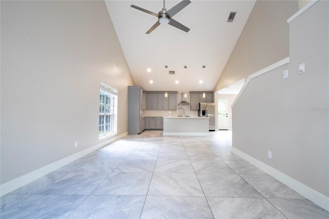 unfurnished living room with high vaulted ceiling, sink, and ceiling fan