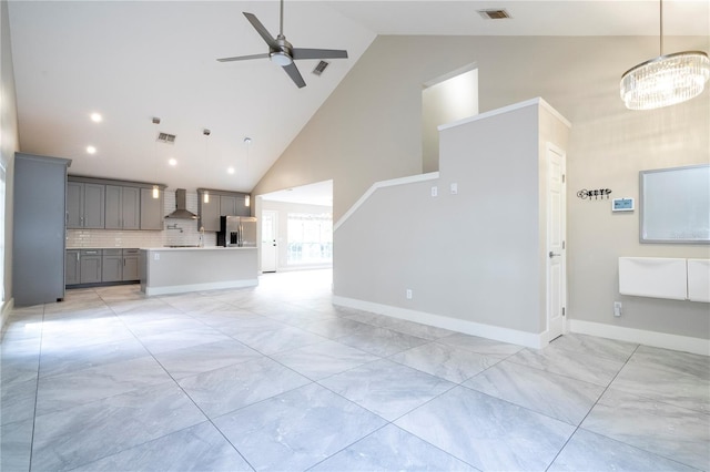 unfurnished living room with high vaulted ceiling and ceiling fan with notable chandelier