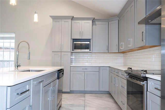 kitchen with wall chimney exhaust hood, stainless steel appliances, sink, gray cabinets, and lofted ceiling