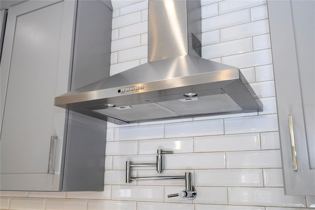 room details featuring wall chimney exhaust hood and white cabinets