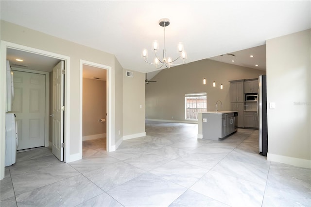 spare room with visible vents, lofted ceiling, washer / clothes dryer, a sink, and a notable chandelier