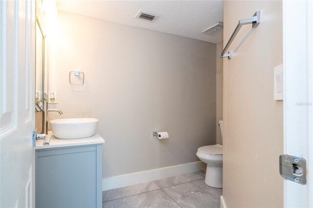 bathroom featuring a textured ceiling, vanity, and toilet